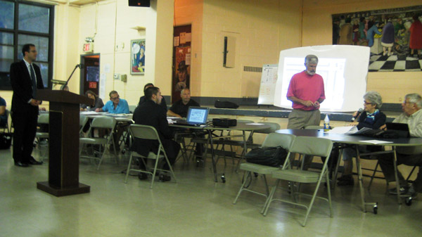 Photo by Eileen Stukane CB4 Land Use Committee co-chair Lee Compton (at right, standing), presided over discussion of the 158-unit, 18-story building planned for a Fulton Houses site currently occupied by a parking lot and a trash compactor.