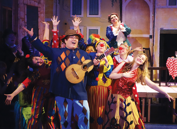 In Amore Opera’s production of “Pagliacci” (double-billed with “The Circus Princess”), Ki-Taek Song, as Arlecchino, is surrounded by the members of the troupe as he sings a love song to Colombina (Michelle Pretto).   PHOTO BY NATHAN HULL