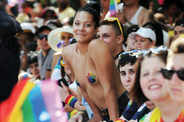 Photos by Milo Hess (Cox; vertical angel wings; “Love and Let Love”; “Born This Way”; mask and whistle); Q. Sakamaki (scaffolding cheerers; soaring angel wings); Jonathan Alpeyrie (woman amid crowd)