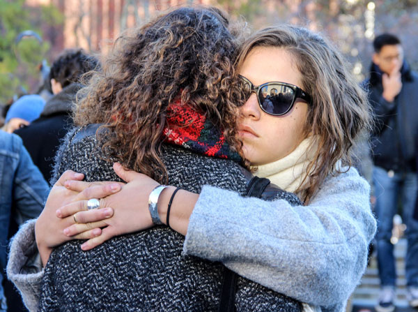 Photo by Tequila Minsky Anais Bambili, left, who had just learned her best friend’s boyfriend died in the Paris attacks, was consoled by her friend Sophie Gousset at Saturday’s vigil in Washington Square. 