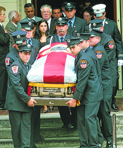 Associated Press / Bebeto Matthews Fallen Firefighter Joseph Graffagnino's wife Linda, center, and the author, behind her, follow behind firefighters carrying his casket after the funeral service at St. Ephrem Roman Catholic Church in Brooklyn in 2007.