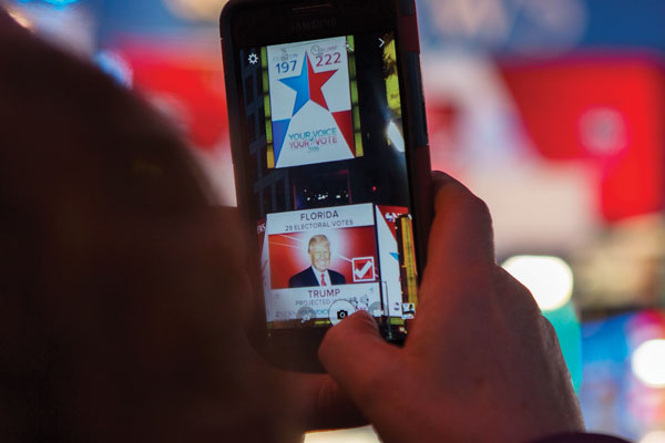 A woman takes a photo to share on social media as TV networks call the swing state of Florida late Tuesday night. Photo by Zach Williams.