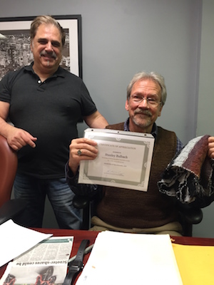 Stanley Bulbach, seated, shows the certificate given for his tenure as head of the West 15th Street 100 and 200 Block Association. Also pictured is Kimon Retzos of the block association. Photo courtesy Steve Starosta. 