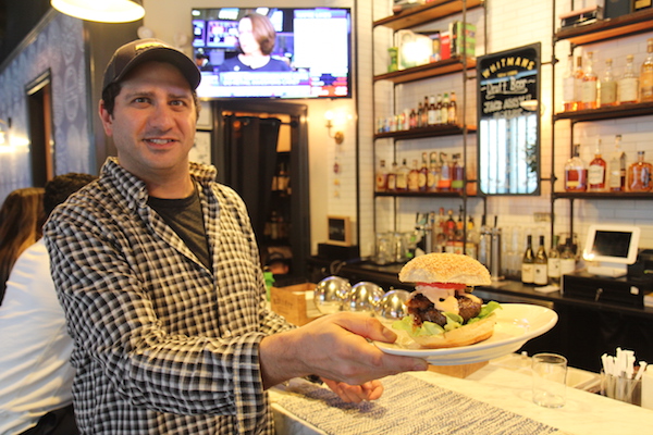 Larry Kramer shows off Whitmans’ flagship Juicy Lucy burger, a take on a Minnesota tradition of stuffing patties with cheese (the Whitmans version is stuffed with pimento). Photo by Dennis Lynch.