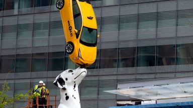 statue of a Dalmatian balancing a real taxi cab on its nose