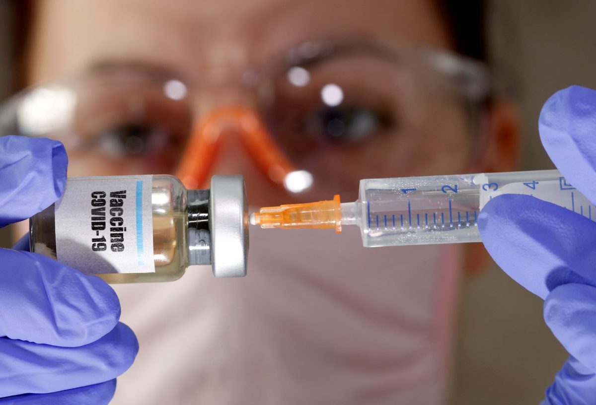 FILE PHOTO: A woman holds a small bottle labeled with a “Vaccine COVID-19” sticker and a medical syringe in this illustration