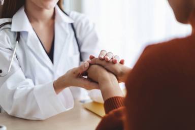 Asian doctor woman encourage young woman patient by holding hand