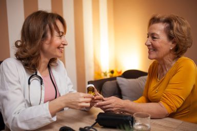 Mid adult female doctor talking with senior patient during house call visit