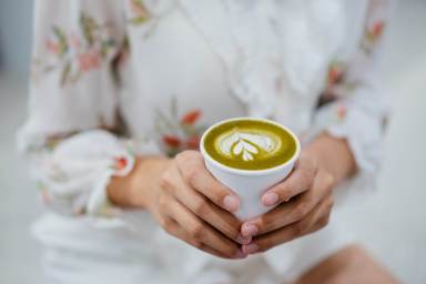 An Asian Chinese woman holding a cup of matcha latte