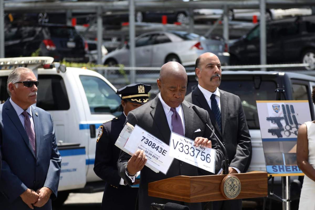 Mayor Eric Adams holds a couple of phony license plates at a briefing in Queens