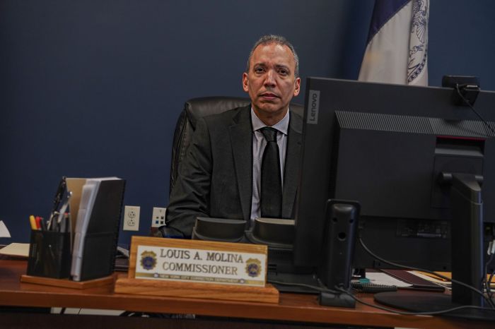 Former Correction Commissioner Louis Molina sitting at desk with nameplate