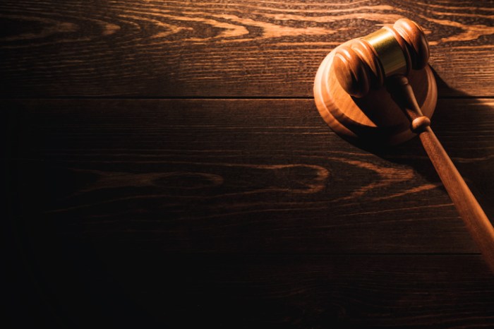 Wooden judge gavel hammer on wooden table background. Dramatic light. Copy space.