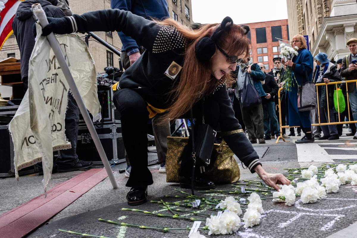 A woman places a carnation in memory of a relative who perished in the fire