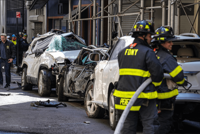 Firefighters remove totaled cars from the garage and check them for human remains