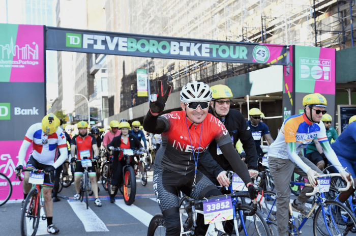 A rider gives a peace sign near the starting line of the 2023 Five Boro Bike Tour