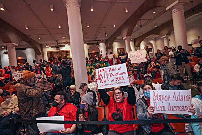 Tenants and advocates hold up signs and boo the proceedings at the Rent Guidelines Board meeting