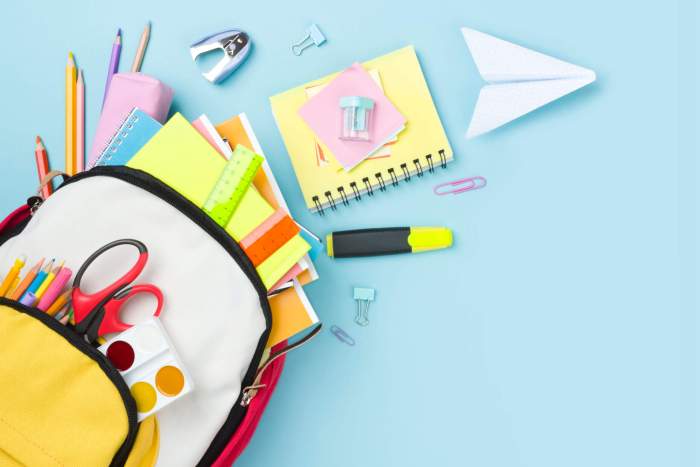 Many colorful school supplies and backpack arranged on blue background