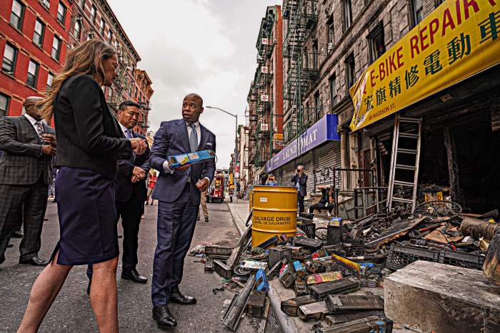 Mayor Adams inspects lithium-ion batteries at the scene of a deadly fire at a Chinatown bike shop