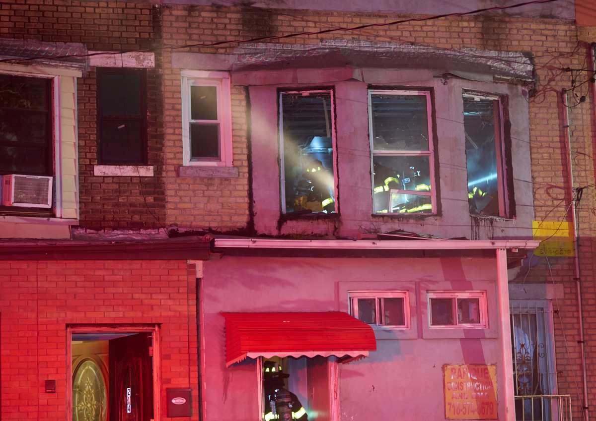 A mother impacted by the fire runs with her child from the fire building at 212 Forbell Street