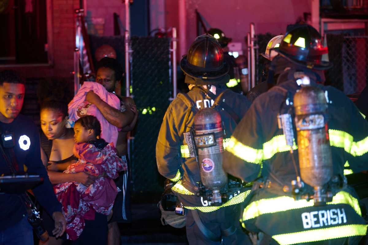 A mother and father impacted by the fire runs with children from the fire building at 212 Forbell Street