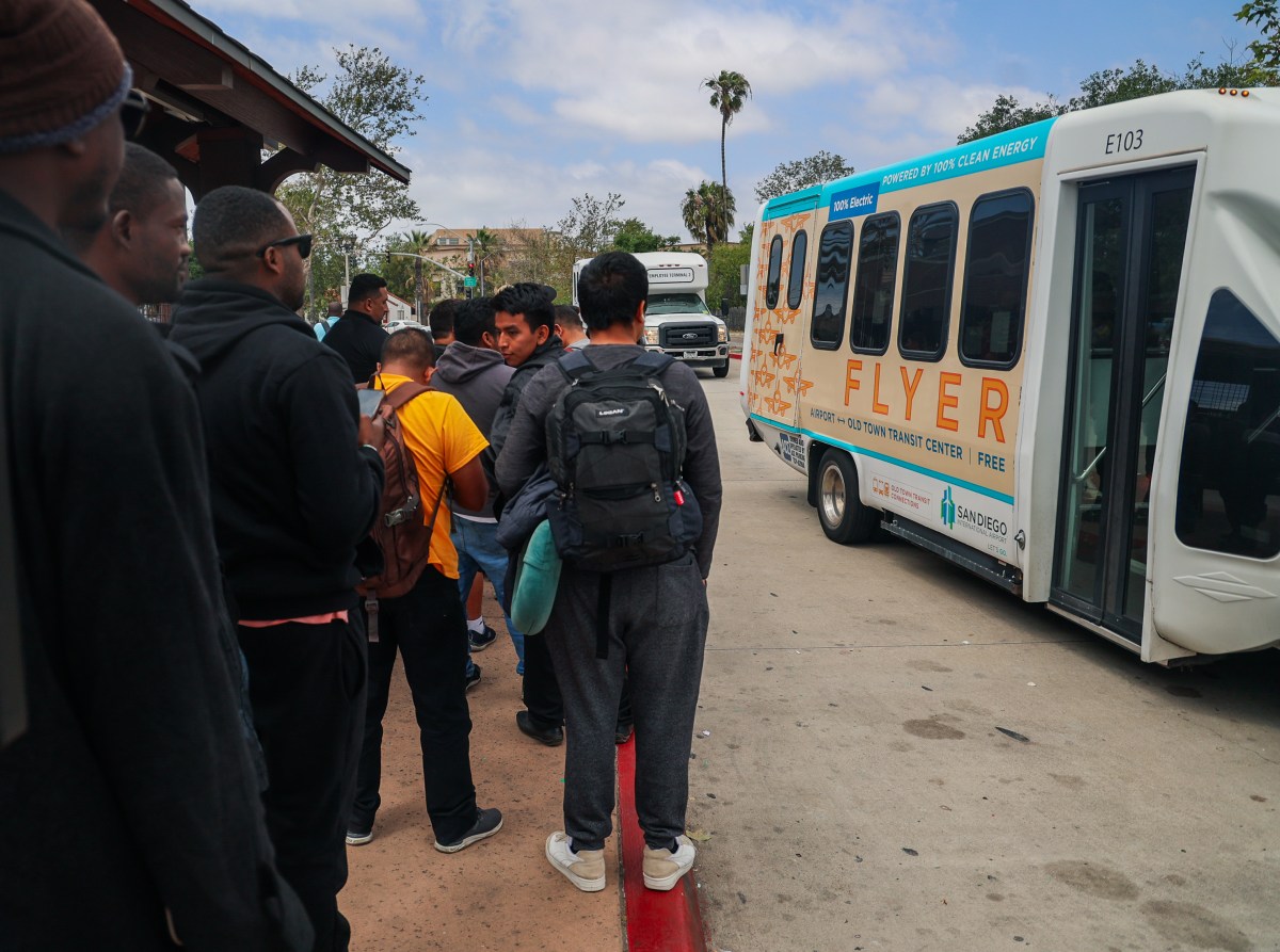Adoum lines up to board a bus with fellow migrants in California