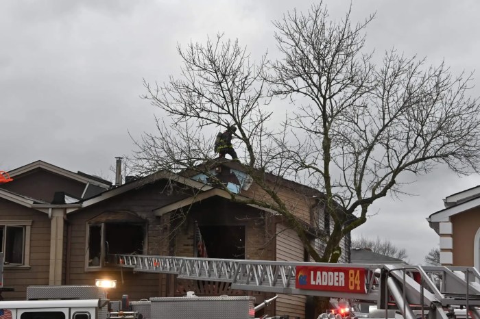 firefighter on the roof of a house in Staten Island, putting out a fire