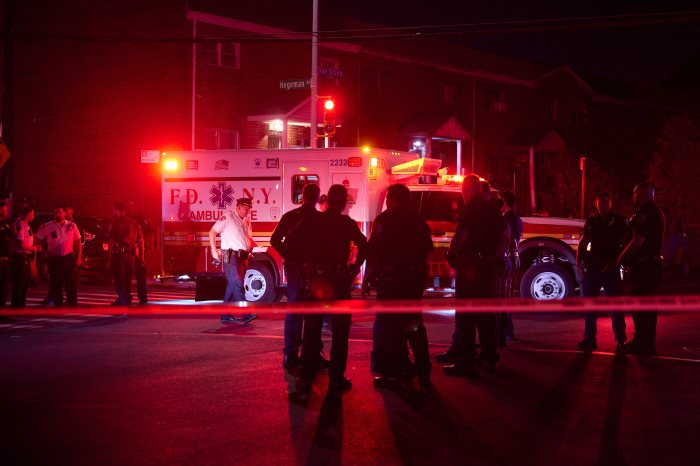 Brooklyn crime scene at night with NYPD officers standing near EMS truck