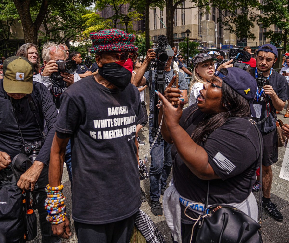 woman seemingly having a wooden American flag jammed into her face while another pair began roughly shoving one another amidst a deluge of humanity