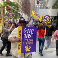 32BJ union workers rally in front of a building in Midtown