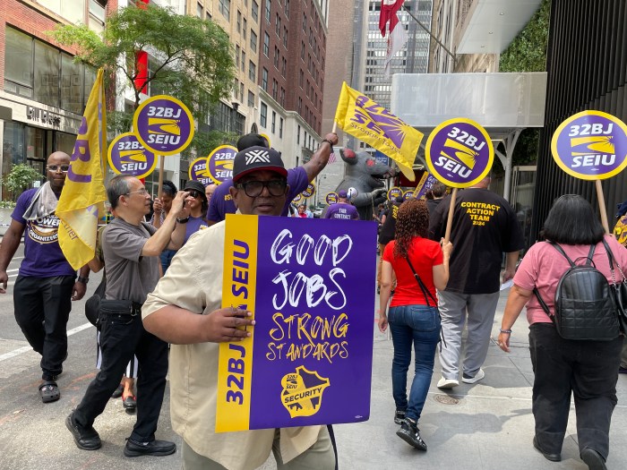32BJ union workers rally in front of a building in Midtown
