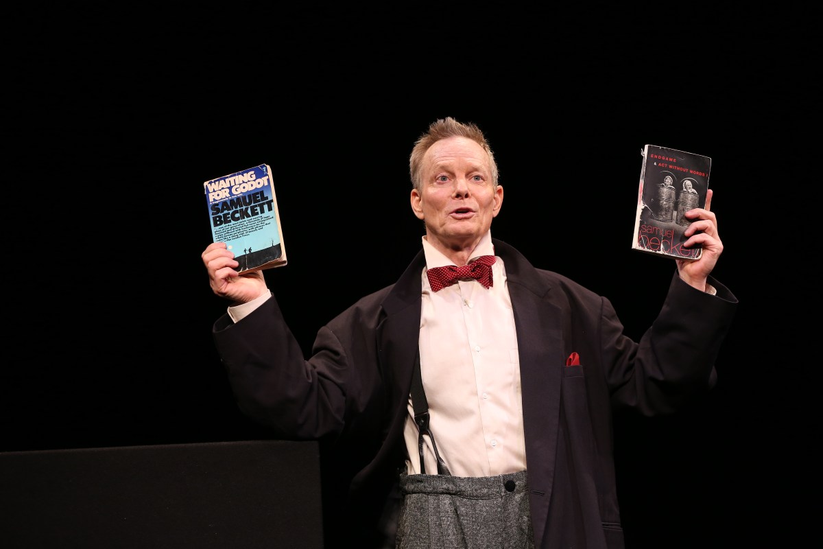 Bill Irwin holding up two books in "On Beckett"