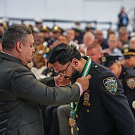 NYPD commissioner places medal of honor around officer's neck before applauding crowd