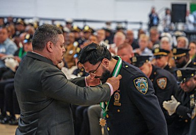 NYPD commissioner places medal of honor around officer's neck before applauding crowd