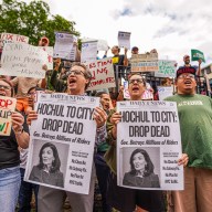 congestion pricing supporters hold signs blaming Kathy Hochul for pausing program
