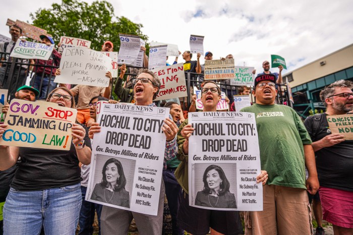 congestion pricing supporters hold signs blaming Kathy Hochul for pausing program