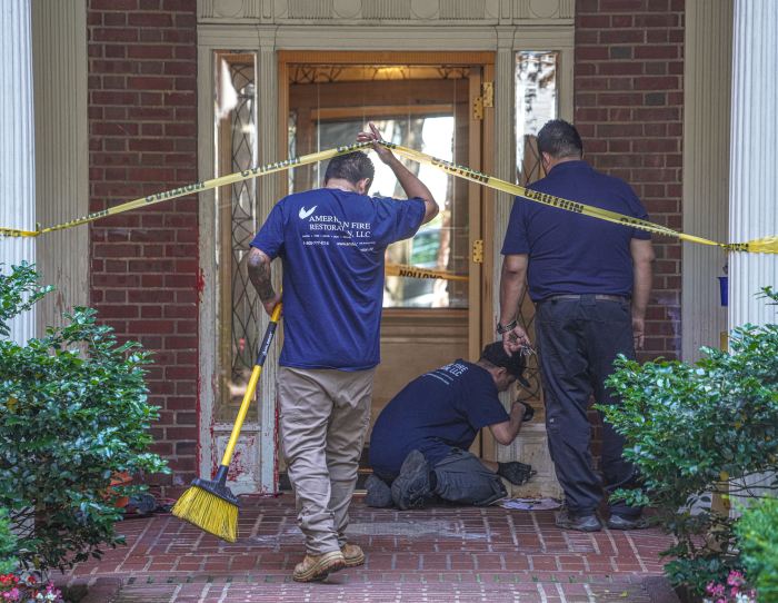 cleanup crew removes red paint on building