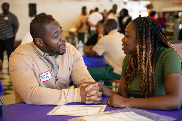 man and woman at a table talking to each other at Sing Sing Correctional Facility. 