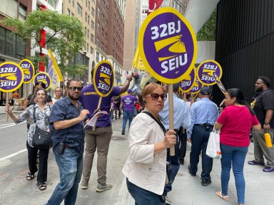 32BJ union members holding signs and in the daytime rally in Midtown to protest wage cuts