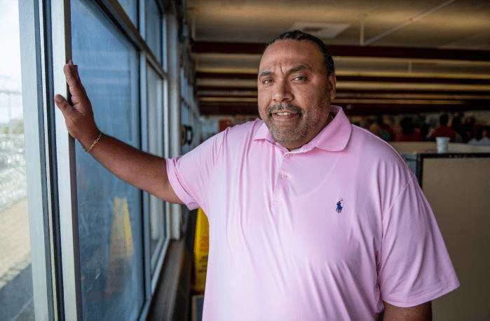 man in pink shirt standing by a window