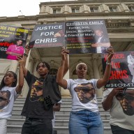 Rally goers hold signs demanding that the NYPD report the truth about Christin Emile's shooting death