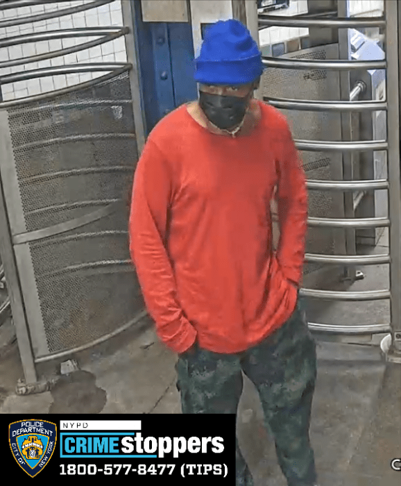 man in Brooklyn train station wearing blue hat and orange shirt