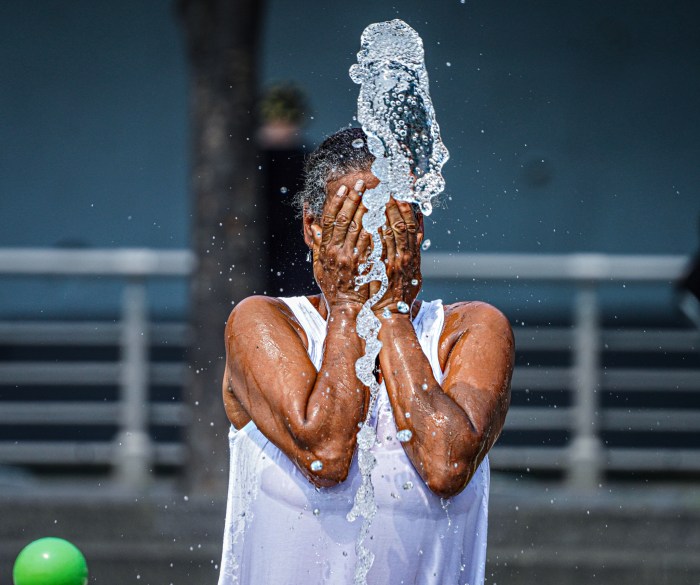 New Yorker splashes face with water during heat wave