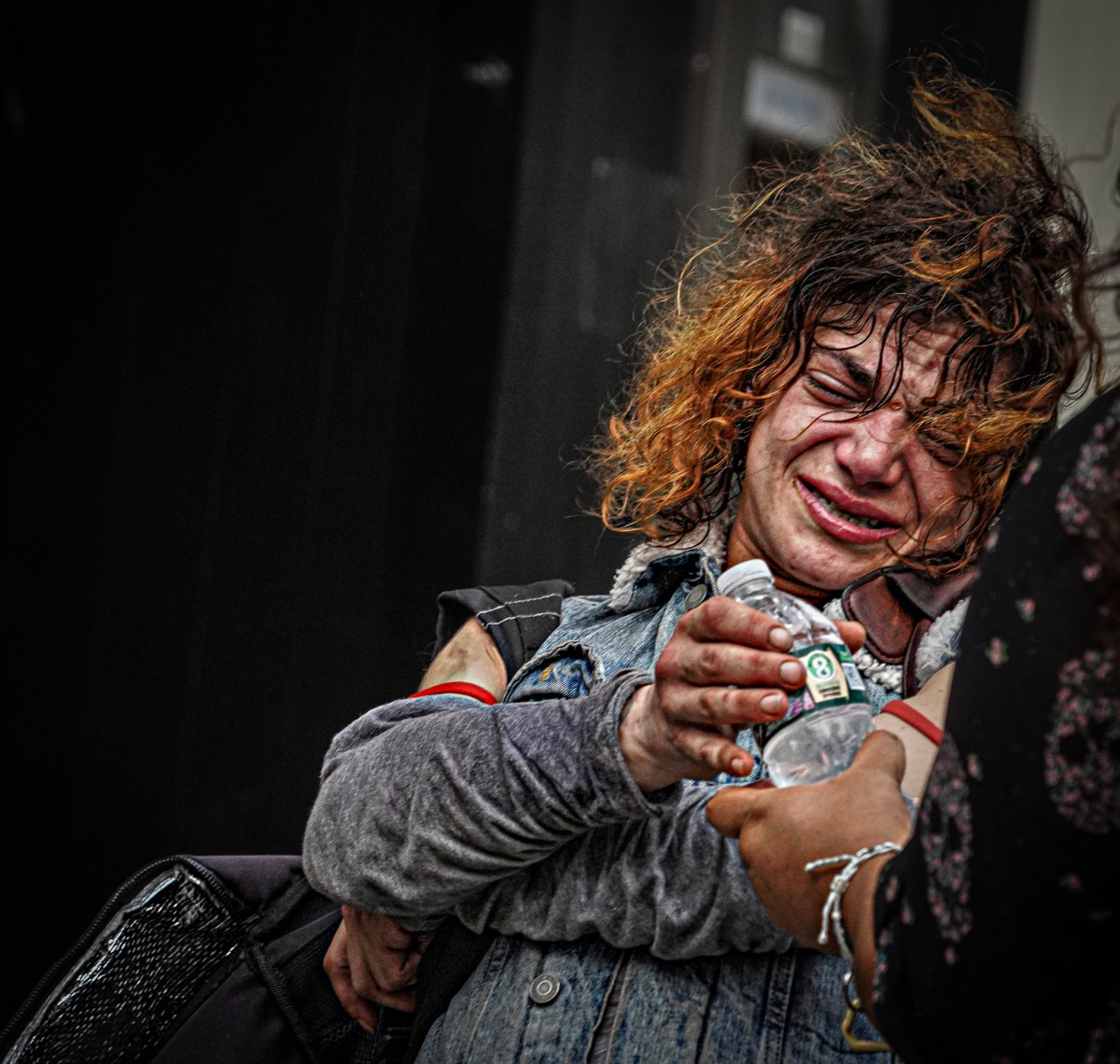 A homeless woman is handed a bottle of water after crying out in pain in the heat