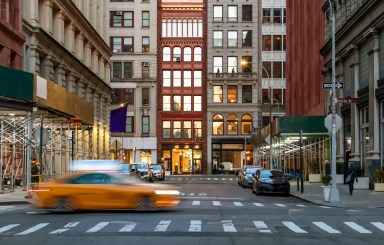 New York City evening street view of the intersection of Washington Place and Broadway in the Greenwich village neighborhood of Manhattan with speeding taxi cab