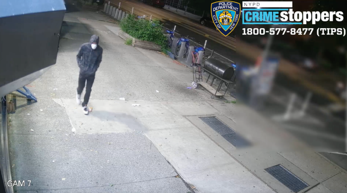 man walking on a street in Crown Heights, Brooklyn wearing a mask and hoodie