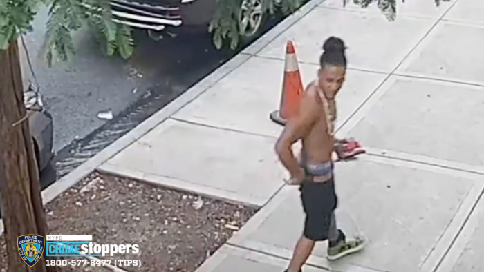 man walking on sidewalk with no shirt on, wanted for assault in Brooklyn