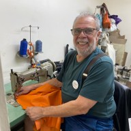 man at a sewing machine at Carlos Falchi handbags studio