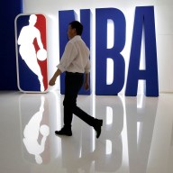 A man walks past an NBA logo at an NBA exhibition in Beijing, China