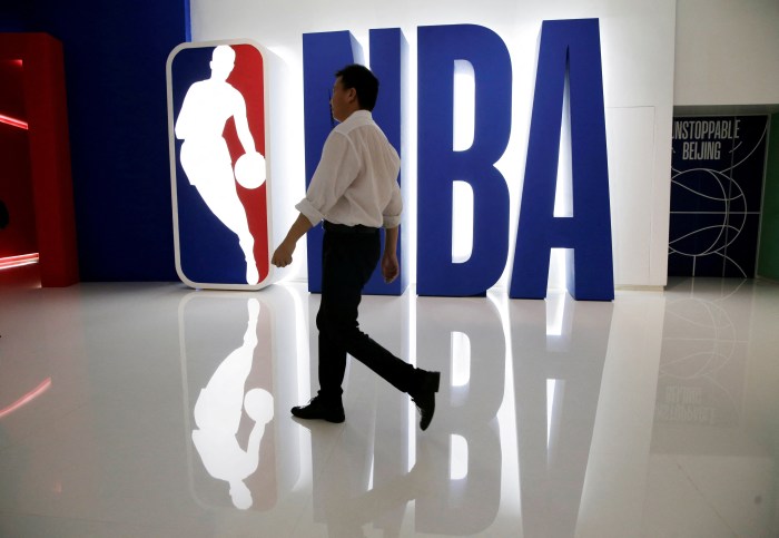 A man walks past an NBA logo at an NBA exhibition in Beijing, China