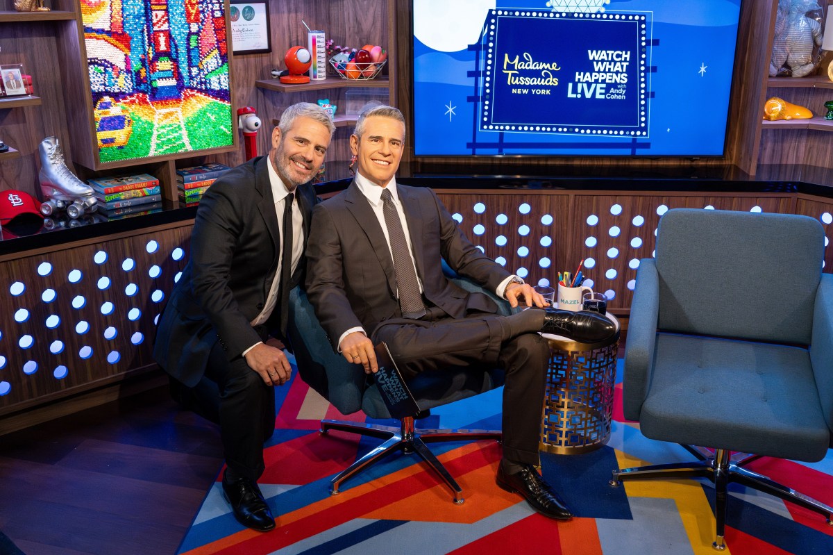 Andy Cohen kneels beside his wax figure